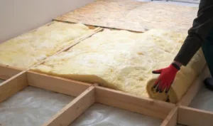 Photo d'un ouvrier installant l'isolant pour isoler le plancher bas d'une maison.