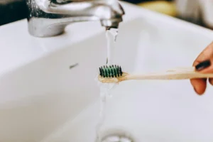 Photo d'un robinet ouvert dont l'eau coule sur une brosse à dent