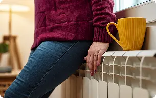 femme posée sur son radiateur imageant le confort thermique offert par un radiateur éléctrique